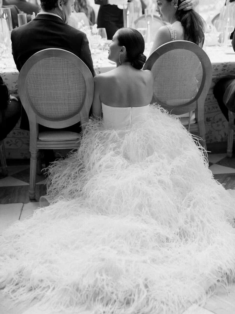 Bride speaking with seated guests at a reception.