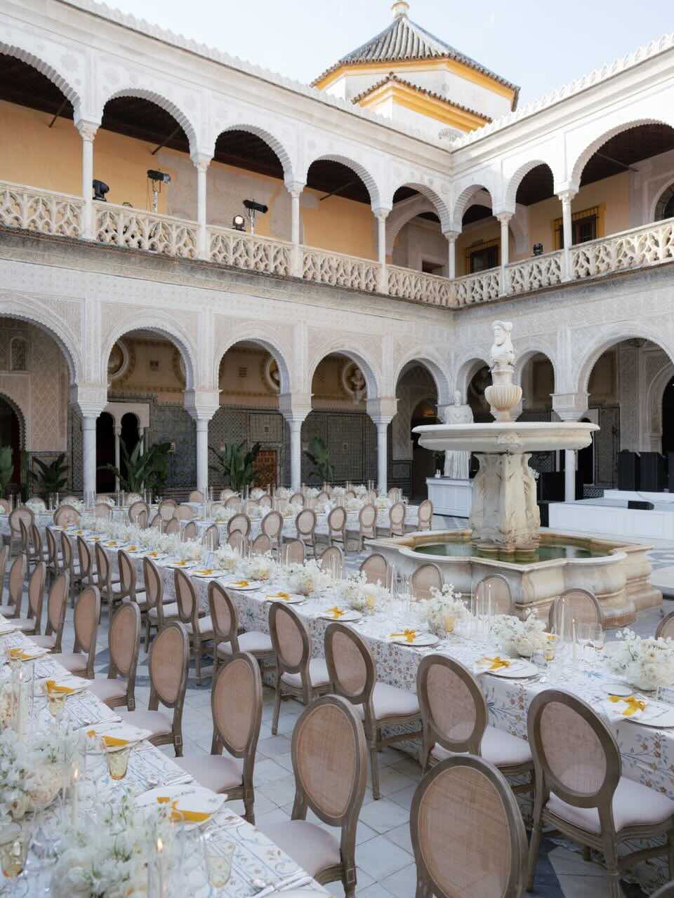 Courtyard with a fountain and tables decorated for a reception.