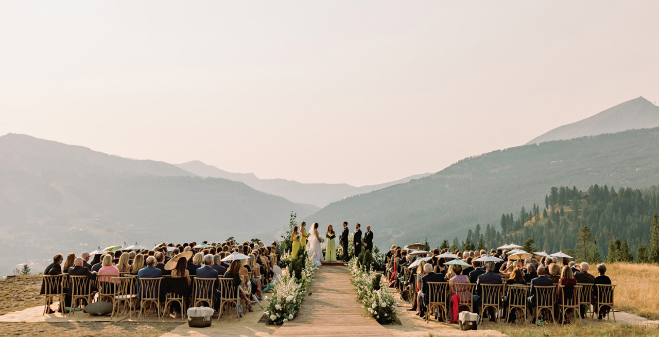 Outdoor wedding ceremony with a valley in the background.